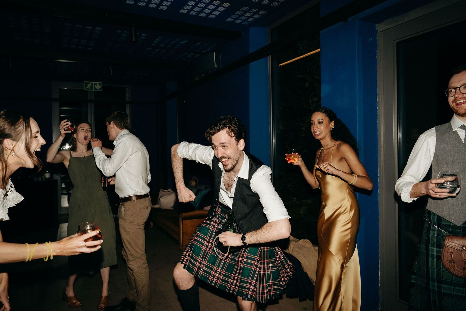 Wedding guests enjoying themselves on the dance floor at a reception in low light conditions.