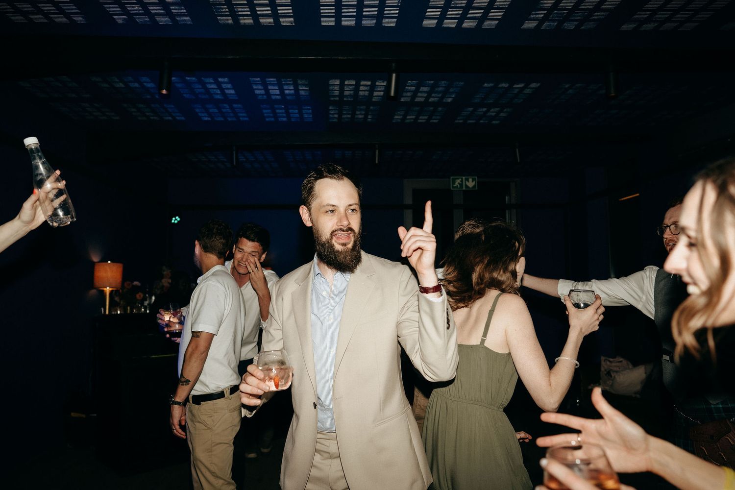 Enthusiastic partygoers dancing and having fun at a dimly lit indoor celebration.