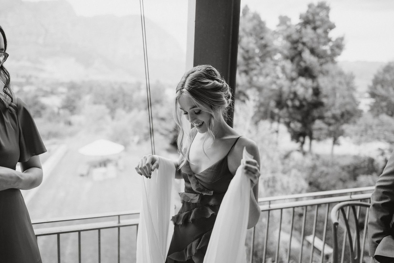 Black and white photo of an outdoor deck as someone in formal attire stands against the railing.