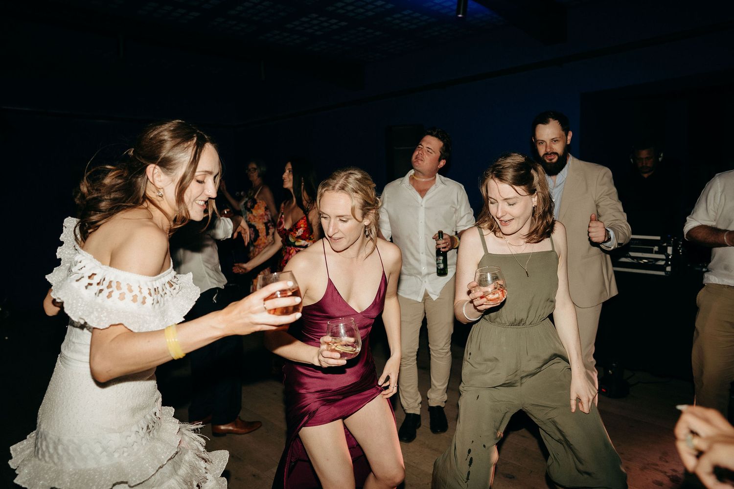 People dance and celebrate at a nighttime wedding reception with guests in formal attire enjoying themselves on the dance floor.