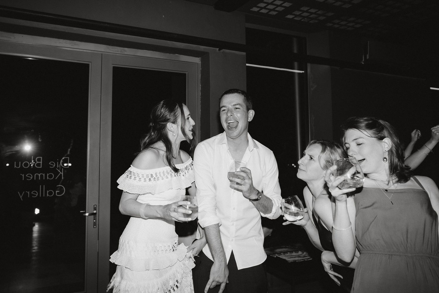 A black and white photo captures people dancing and socializing at a party.