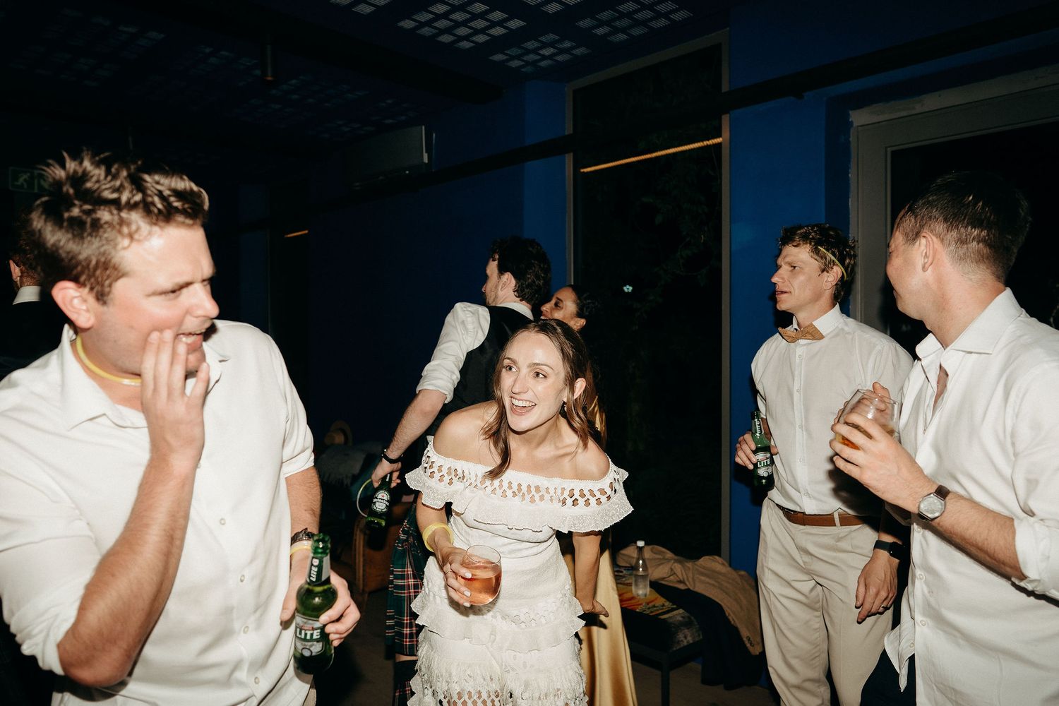 People dancing and socializing at a party with a candid, casual atmosphere in low lighting.