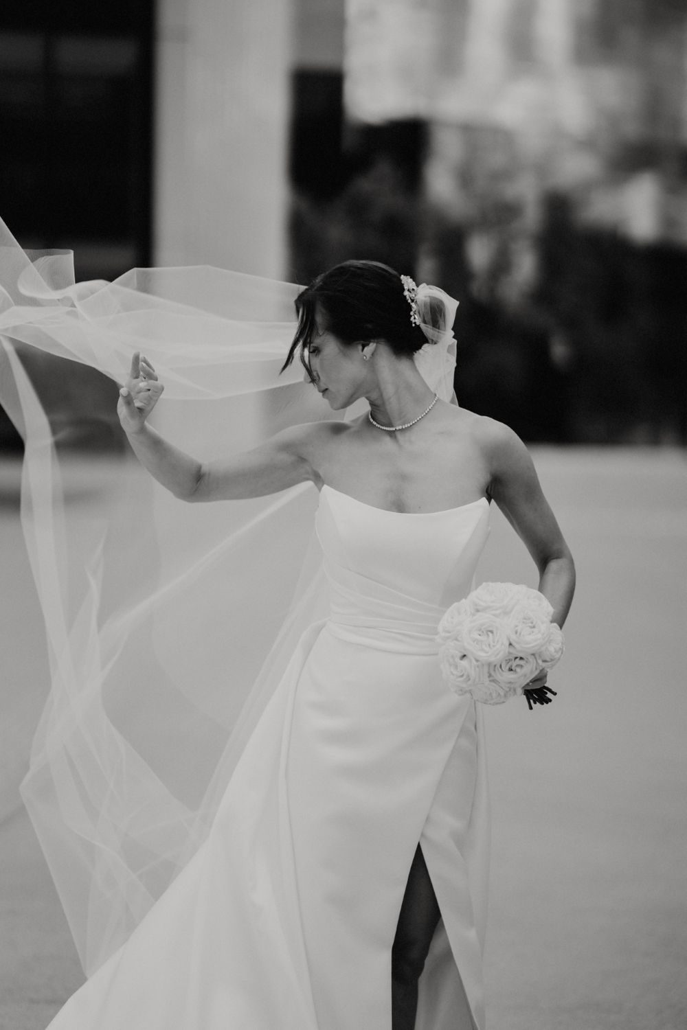 Black and white photo of flowing wedding dress and veil in motion.