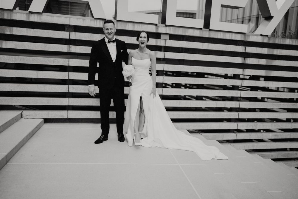 Black and white portrait of couple standing against geometric striped backdrop.