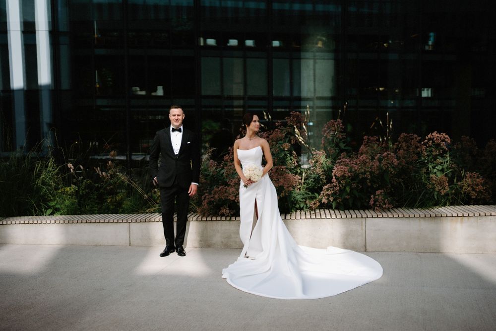 Wedding couple poses against modern landscaping and architectural elements.