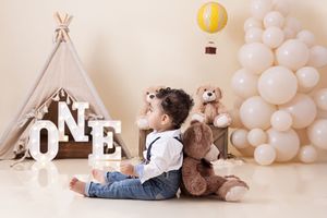White balloon decorations and teepee tent create a dreamy first birthday photo session setup in neutral tones.