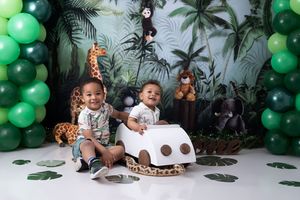 Safari themed birthday party setup with green balloon garlands, palm leaves, and jungle animal decorations.