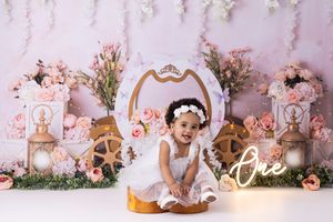 Pink and gold floral backdrop with romantic decorations and vintage frames creates an elegant photo session setting.