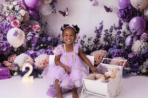Lavender and purple balloon arch with floral decorations creates a dreamy backdrop for a special celebration.