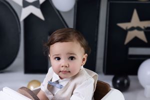 Baby in black and white room with star decorations smiles while sitting in white chair.