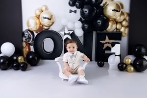 Black and gold balloon decorations with teddy bears create an elegant first birthday party backdrop.