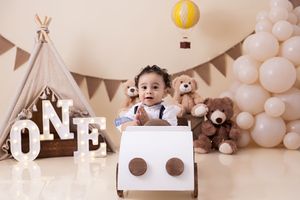 First birthday photoshoot featuring white toy car, teepee tent, teddy bears and balloon decorations.