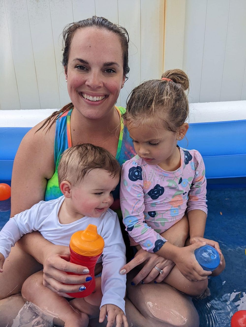 Family enjoying time together in a blue pool with colorful drinking cups.
