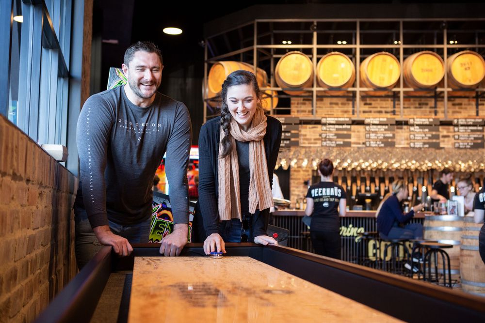 Rustic bar interior with wooden decor and warm lighting showcases multiple craft beer taps and glassware displays.