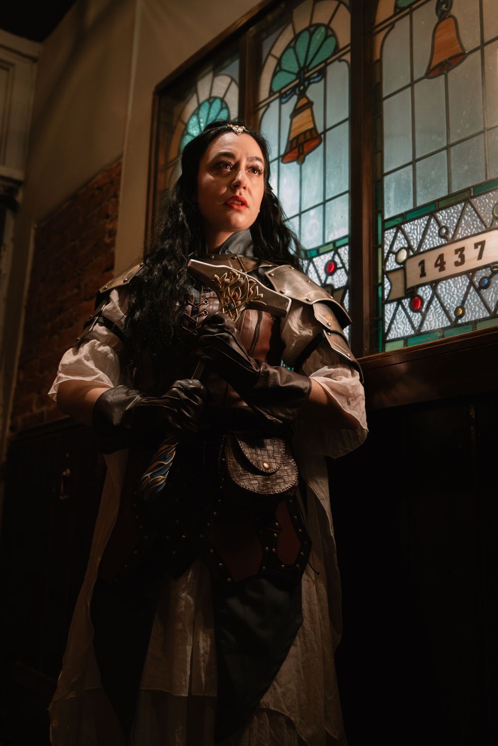 Dramatic fantasy photoshoot in a historic building with stained glass windows and Victorian-style clothing.