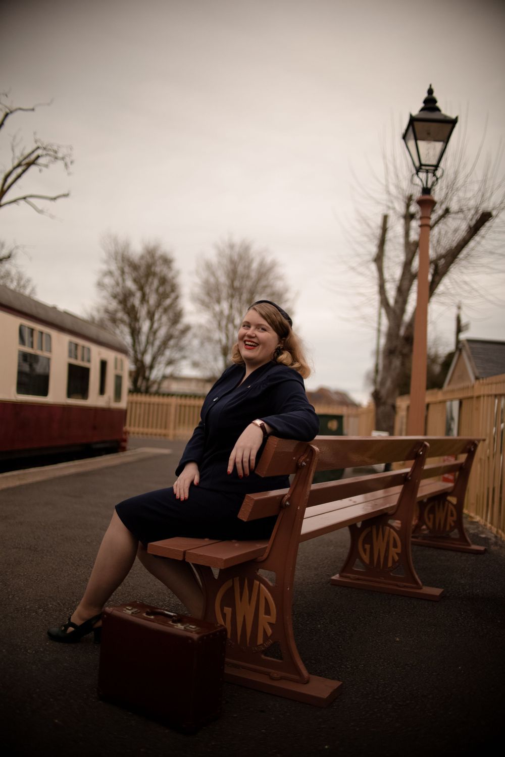 Moody portrait session on wooden benches at dusk with vintage railway aesthetics.