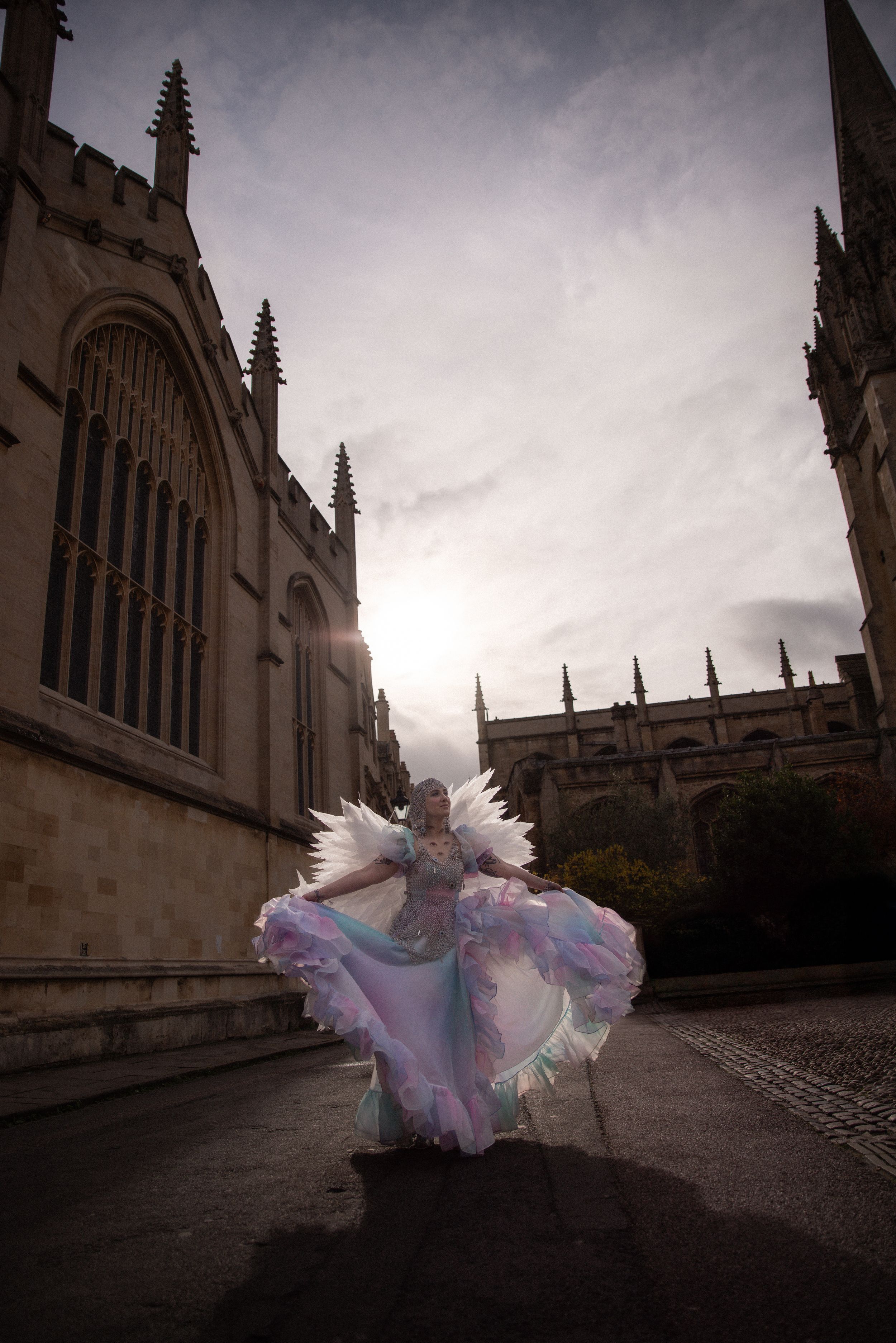 A flowing dress creates dramatic movement against gothic architecture in moody lighting.