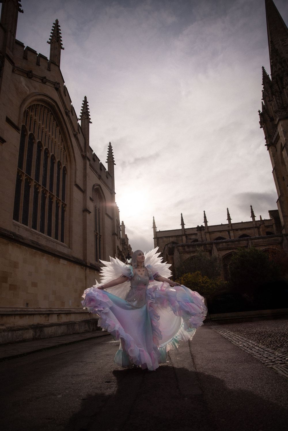 A flowing dress creates dramatic movement against gothic architecture in moody lighting.