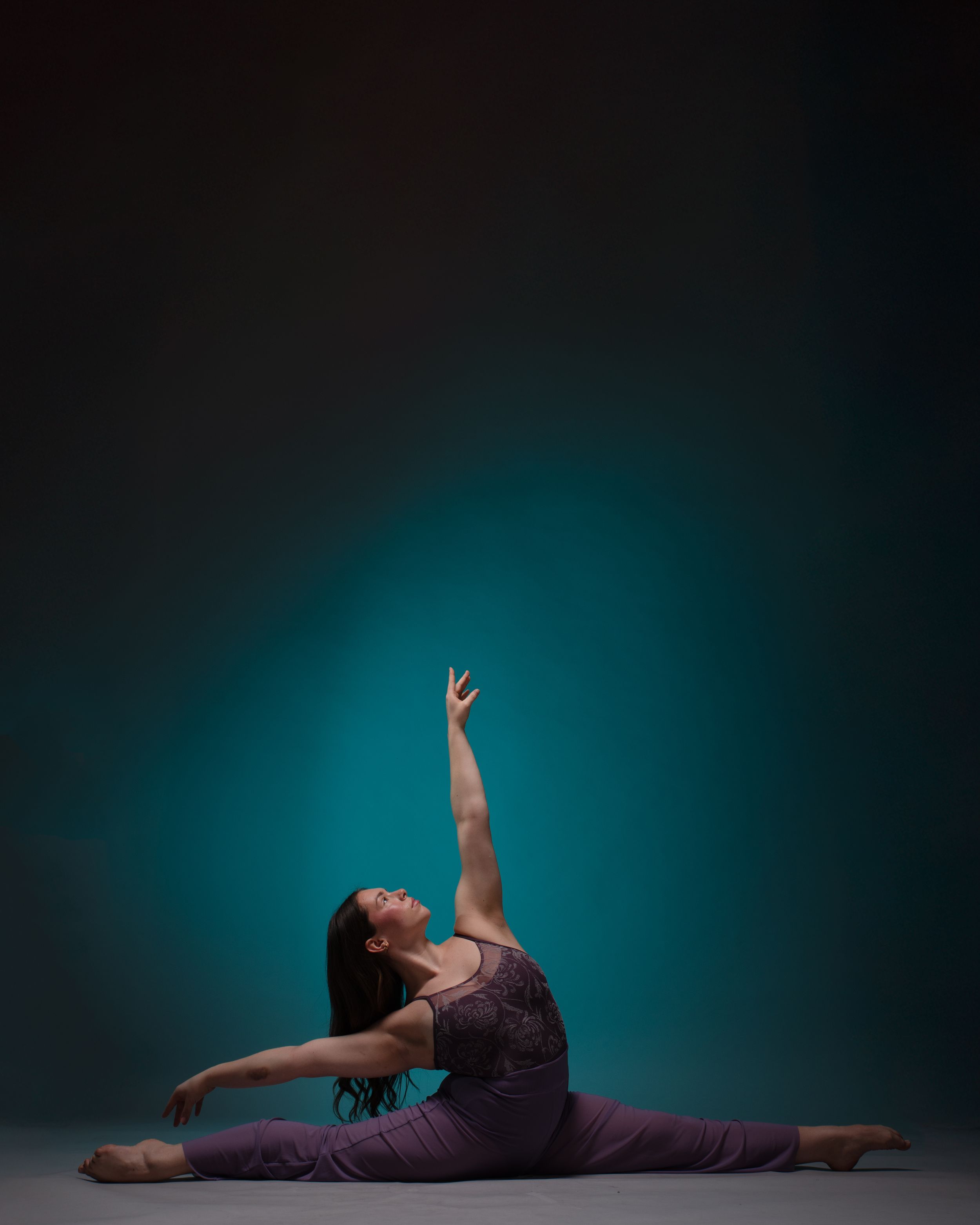 Modern dancer performing expressive movements on floor against blue gradient background.