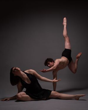 Contemporary dance performance showing fluid movements against dramatic dark background.