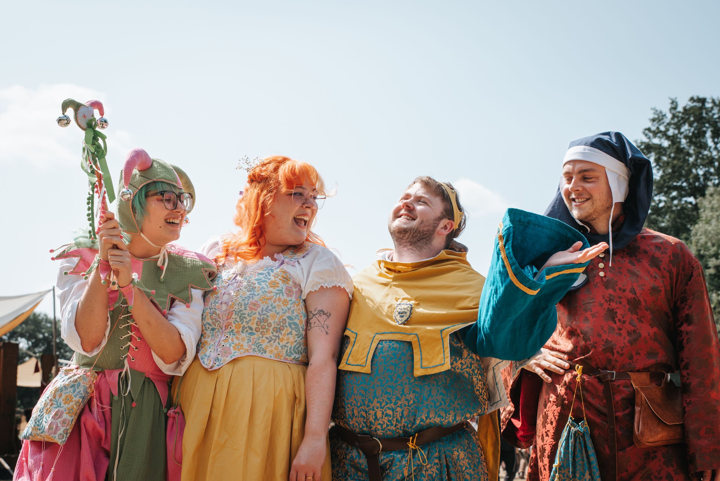 Colorful group wearing vibrant costumes standing in a line against blue sky.