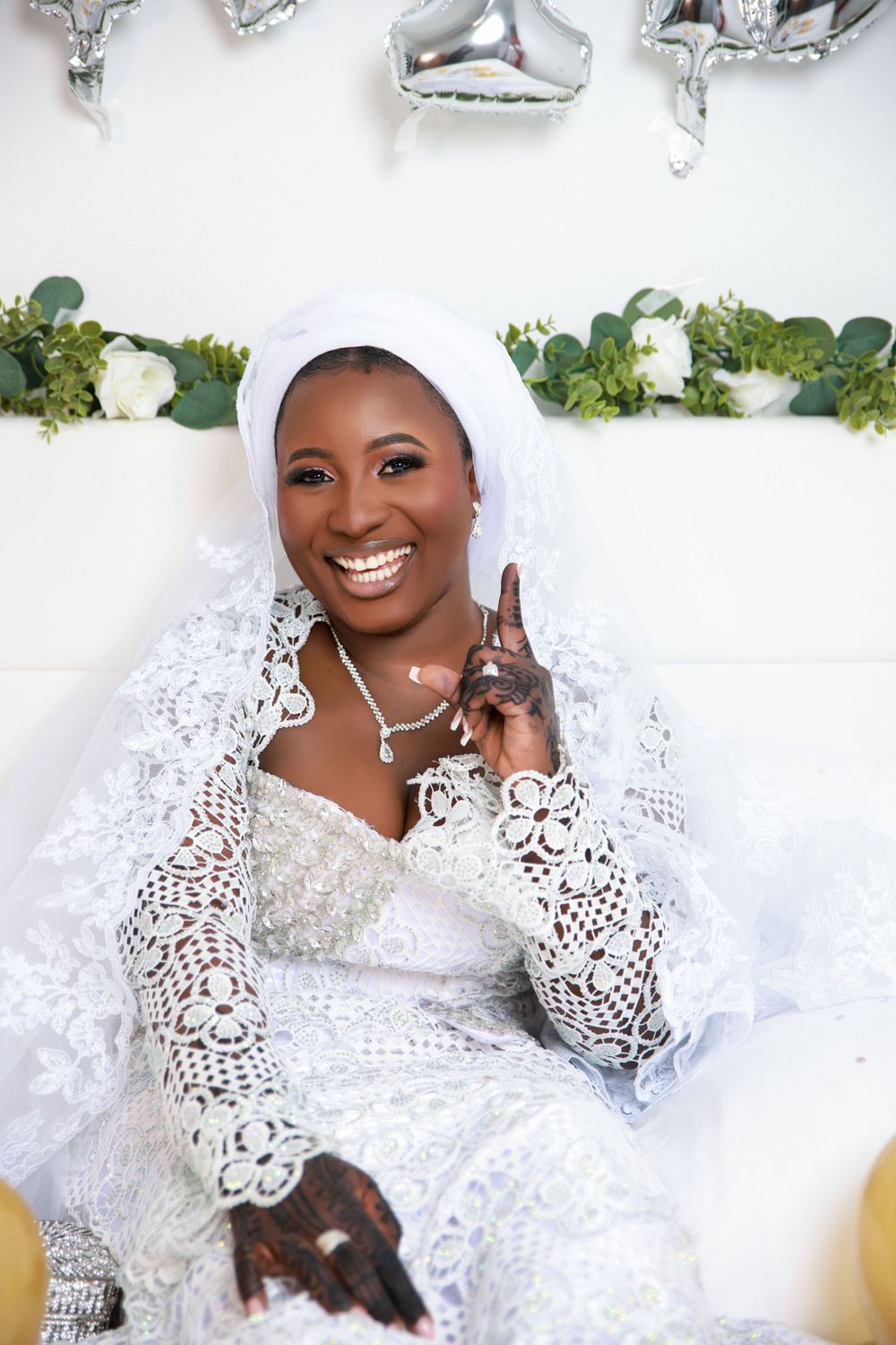 A bridal portrait shoot featuring white lace dress and traditional headpiece against a light backdrop.