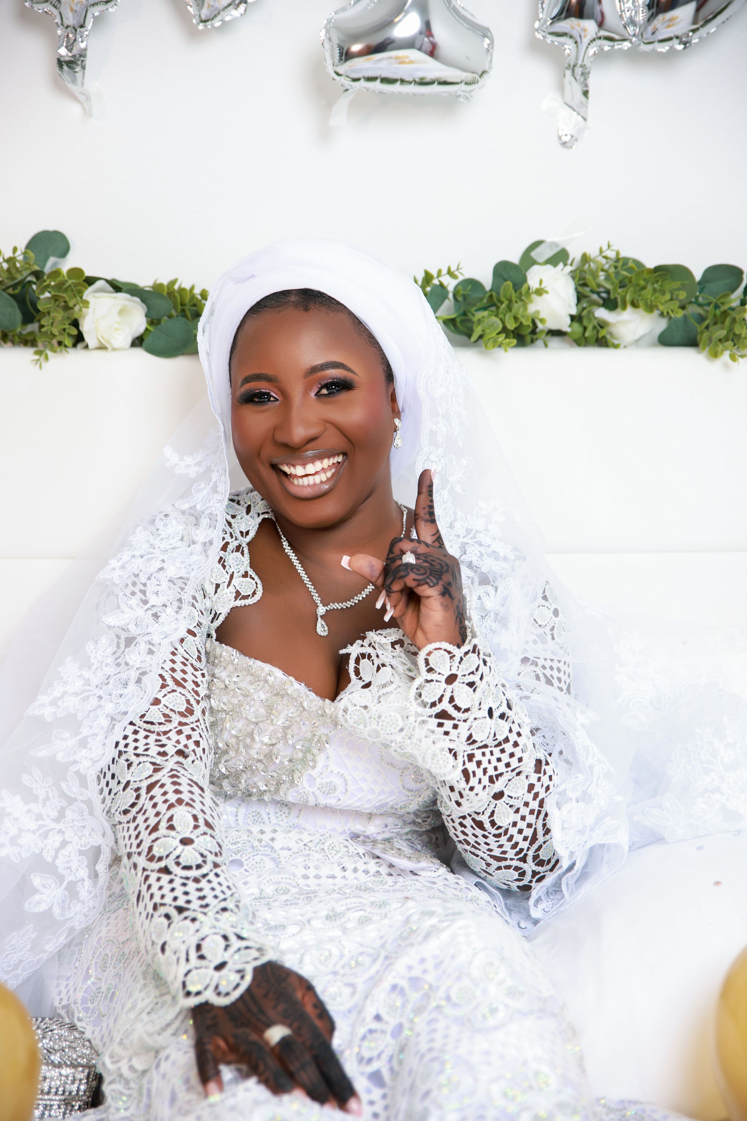 A bridal portrait shoot featuring white lace dress and traditional headpiece against a light backdrop.