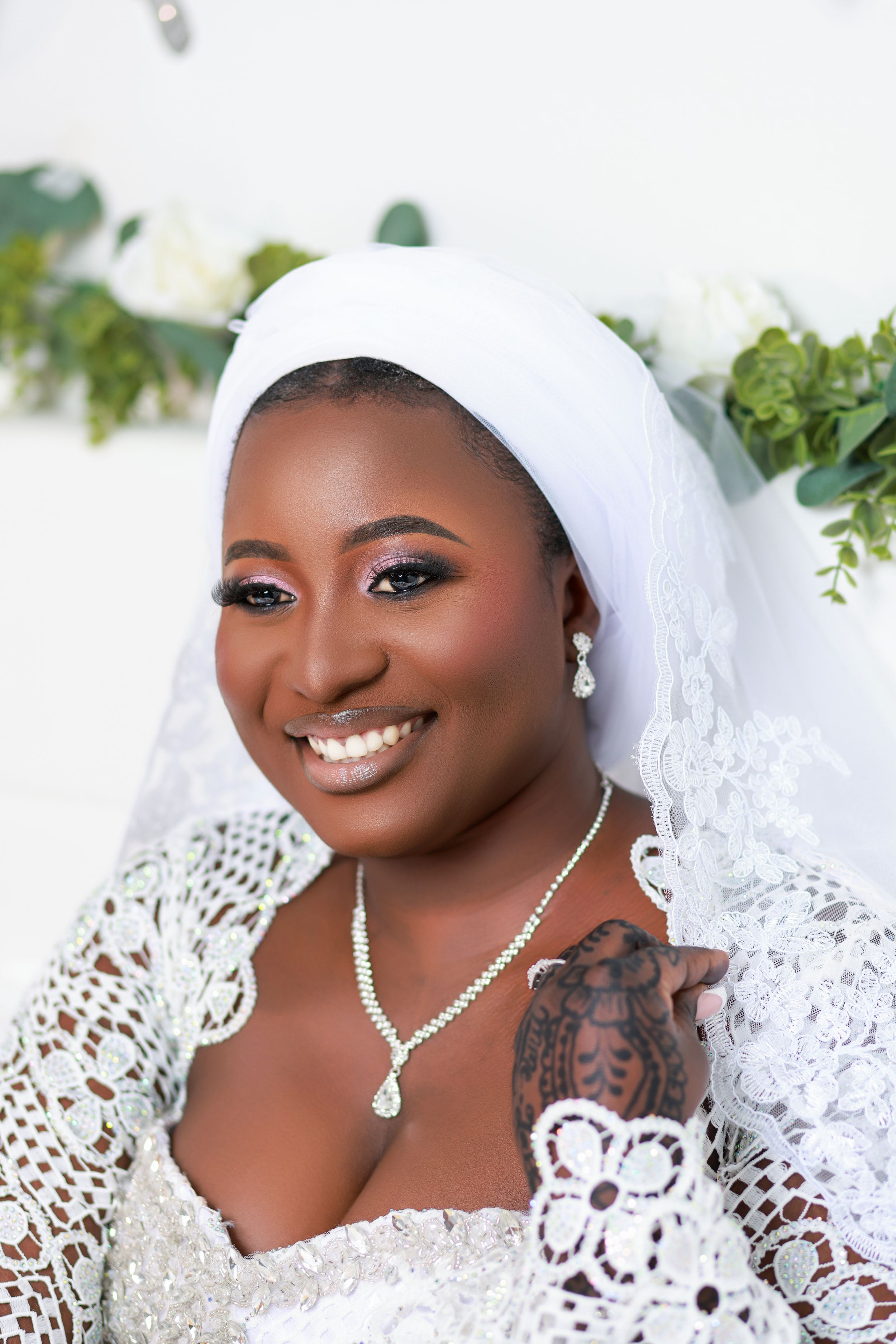 Close-up bridal portrait with pearl jewelry and white lace details against a light background.