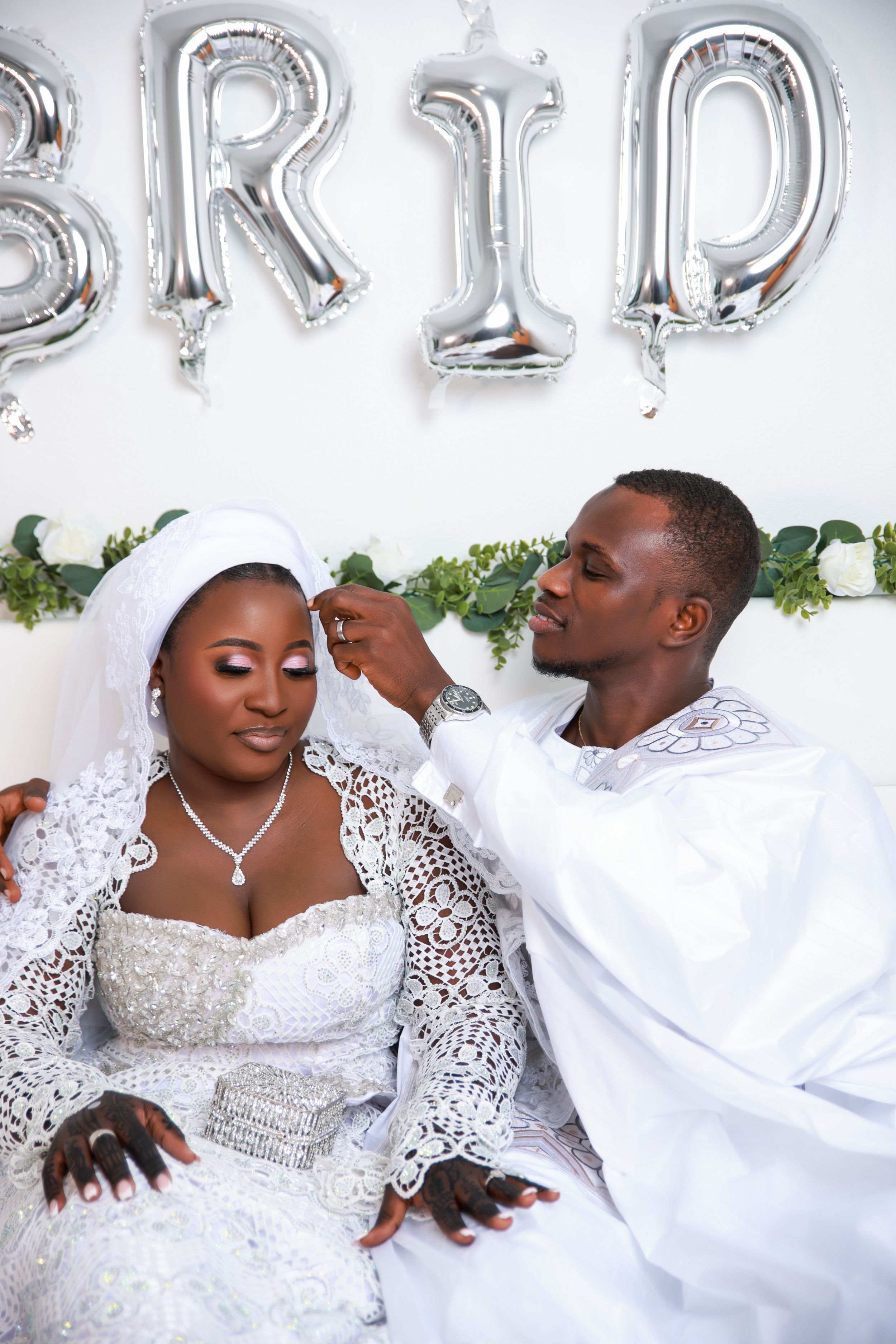 A couple in elegant white attire share romantic moments during a wedding photo session.
