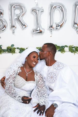 Bride in lace dress and groom in white share joyful moments during wedding photoshoot.