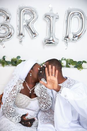 Couple pose playfully during wedding photo session with silver balloon letters.