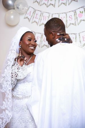 Wedding couple shares candid moments under silver balloon decorations and banners.
