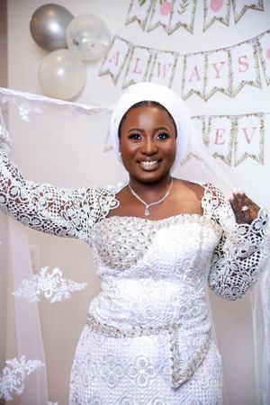 Bride poses in elegant white lace dress with silver balloon decorations.