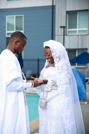 Wedding couple in matching white outfits share candid moments outdoors.