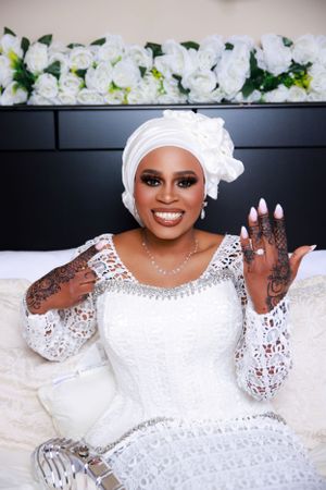 Wedding photography featuring intricate white lace dress and traditional headwrap.