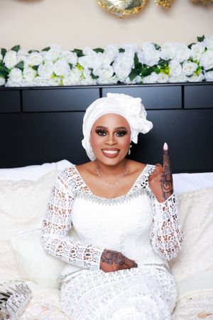 Elegant bridal portrait with white lace dress and traditional headpiece against dark backdrop.