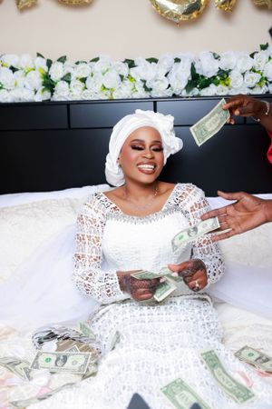 Person in bridal attire plays with cash money during wedding photoshoot.