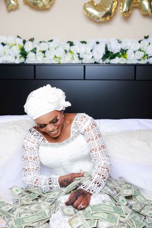 Person in bridal wear plays with money during festive wedding photography session.