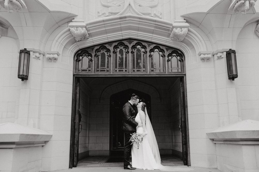 A romantic black and white photograph at an ornate building, captured by Apertured Media Auckland Wedding Photographer.