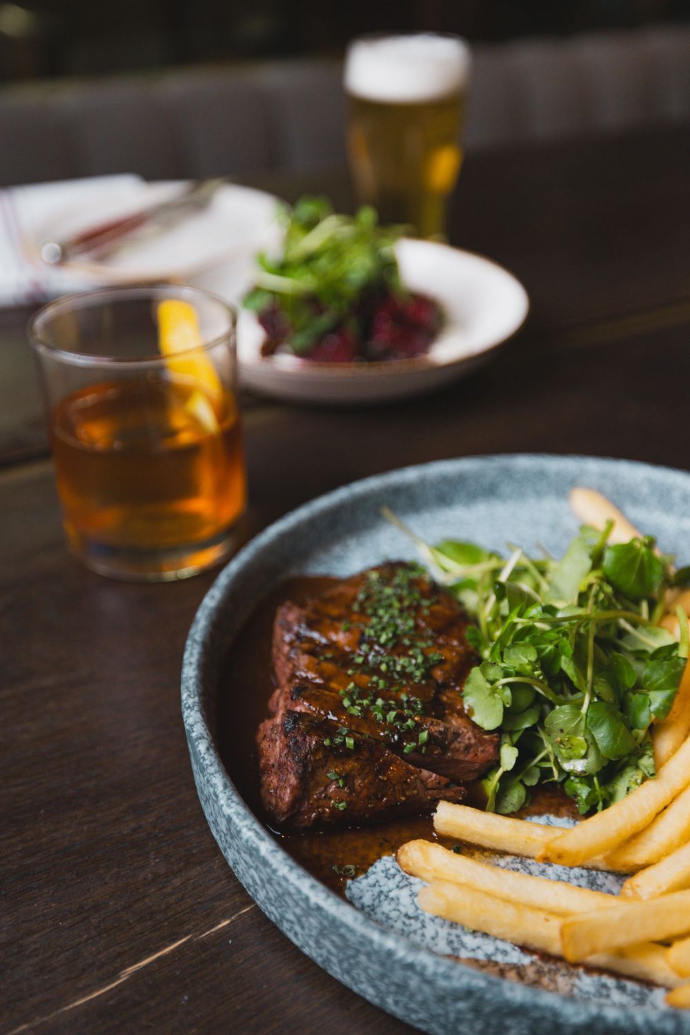 Grilled steak with french fries and salad served with beer and whiskey.