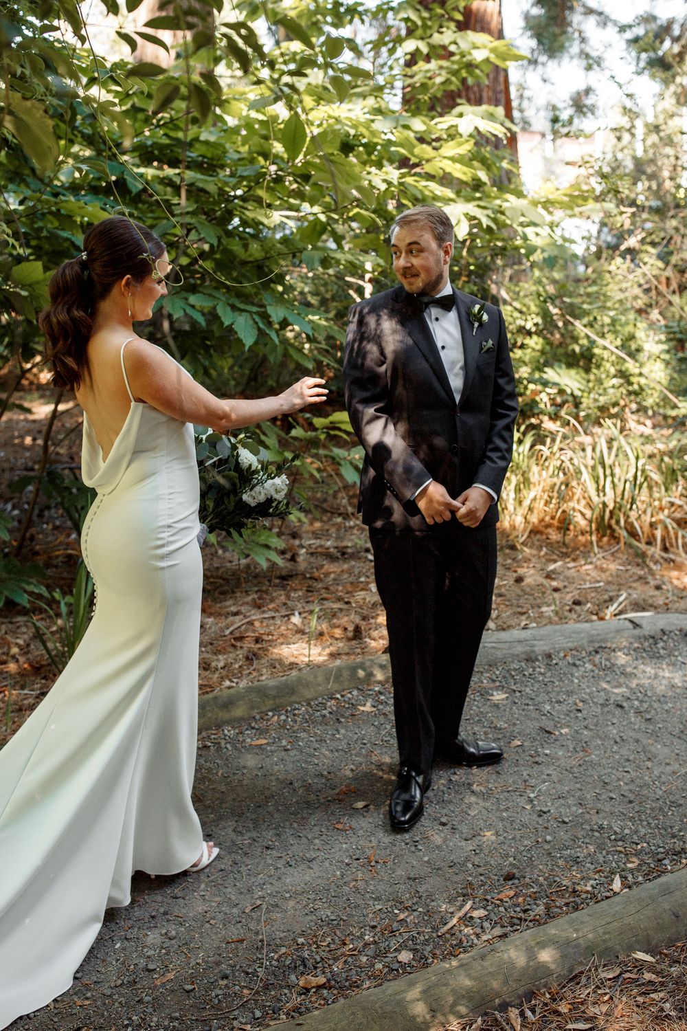 First look moment between couple in formal wedding attire on garden path.