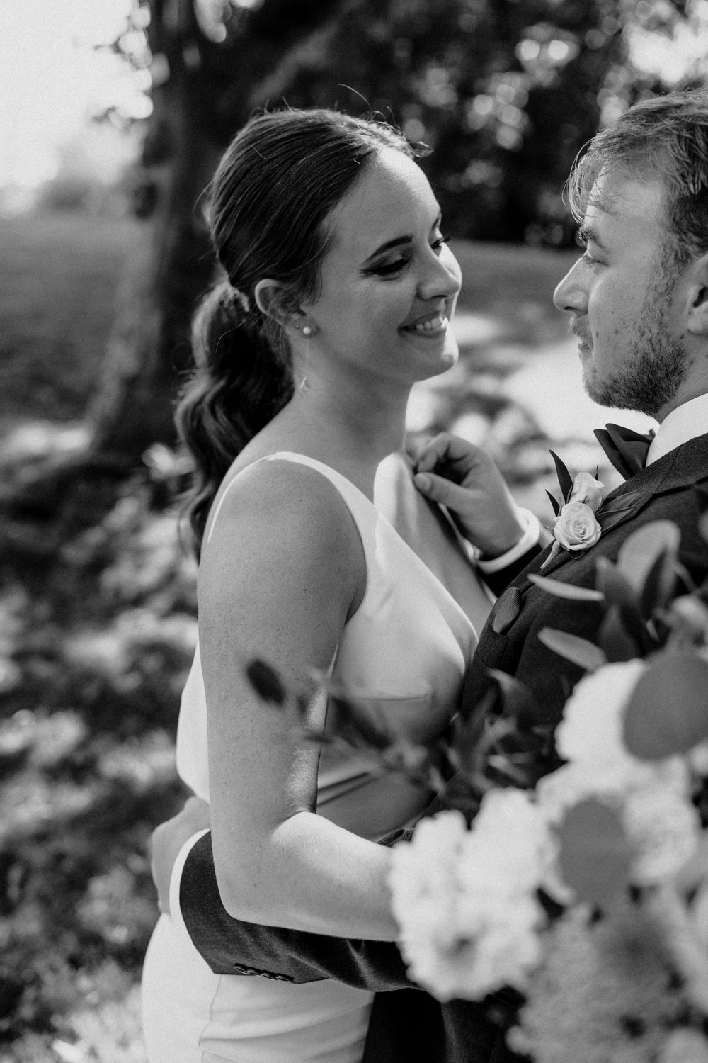 Intimate black and white portrait of newlyweds sharing tender moment outdoors.