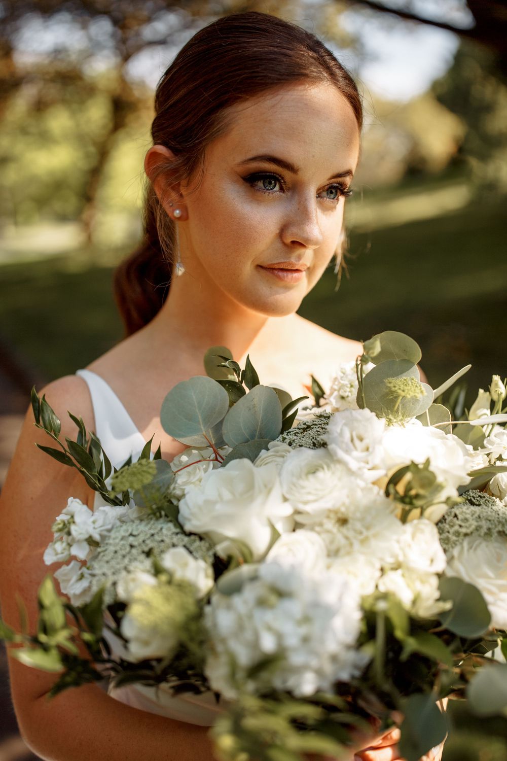 Beautiful bridal portrait showcasing a white and green bouquet in natural outdoor lighting.