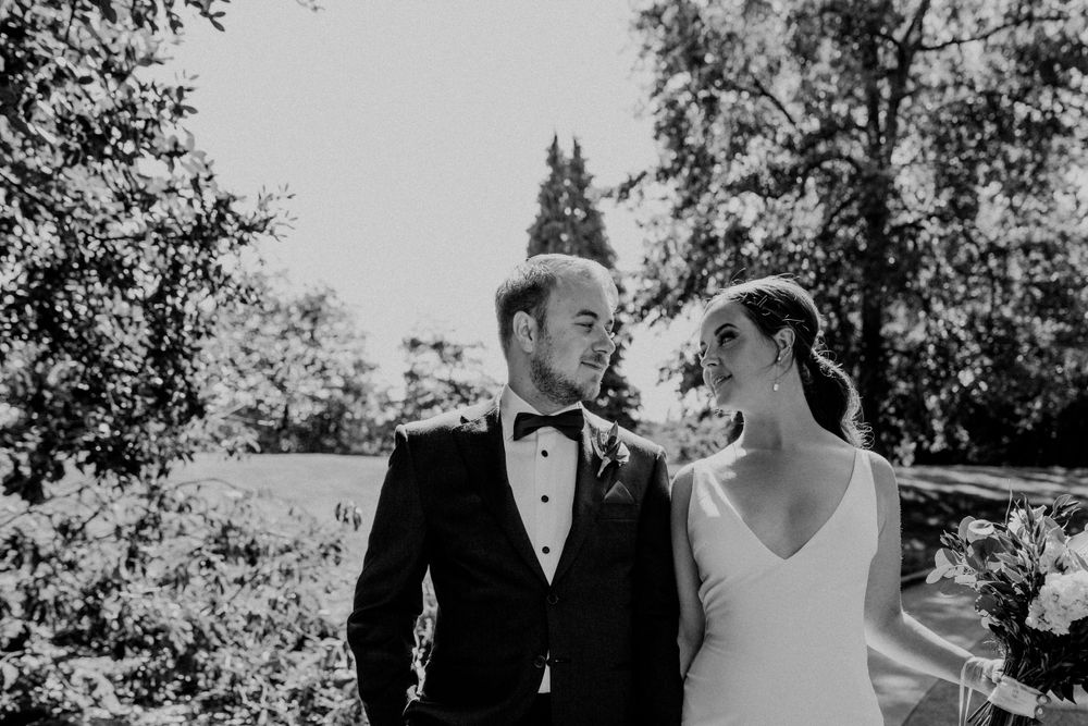 Elegant couple shares an intimate moment during their wedding photoshoot in a garden setting.