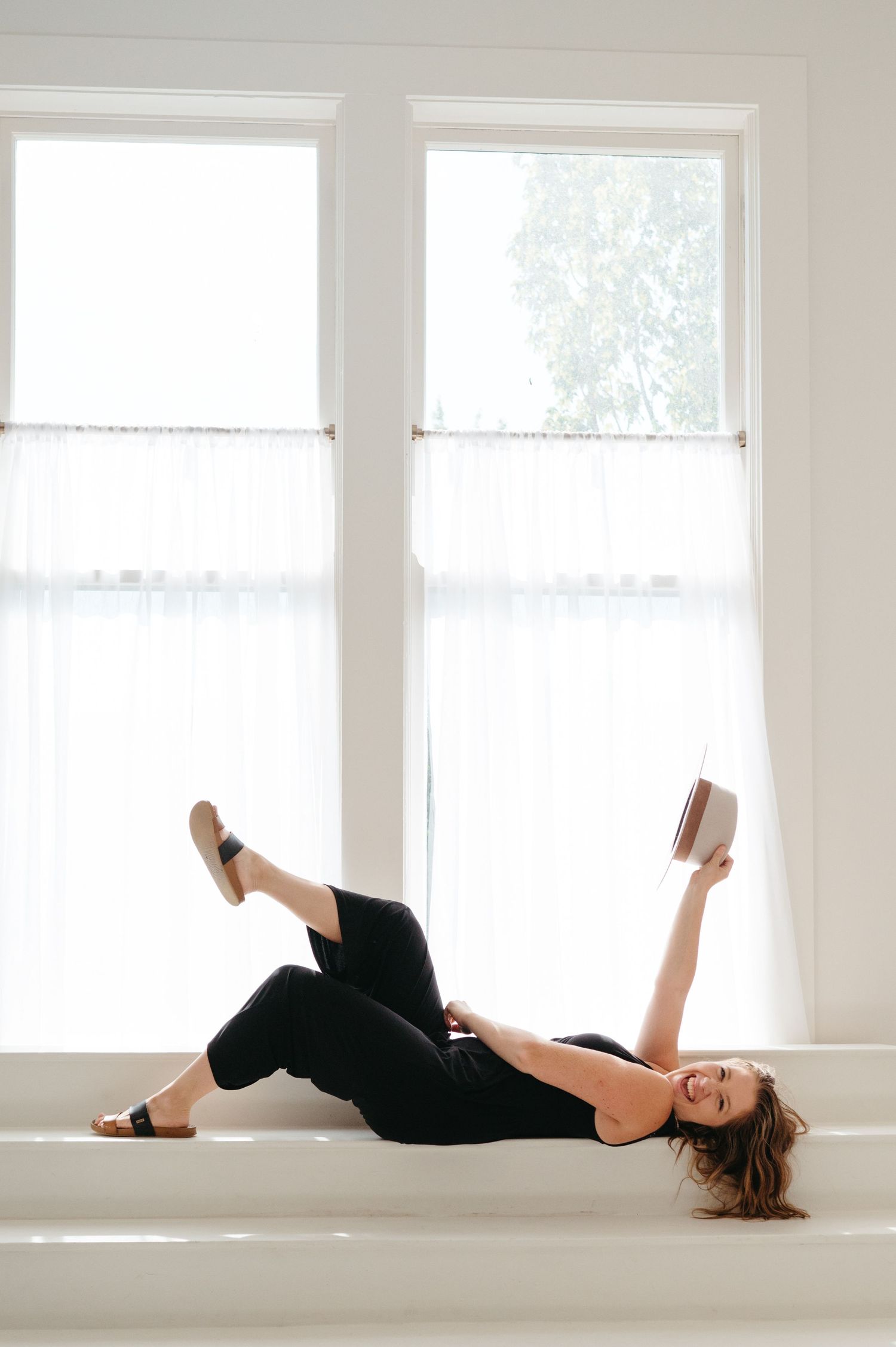A relaxing reading moment by bright windows in an all-white room.