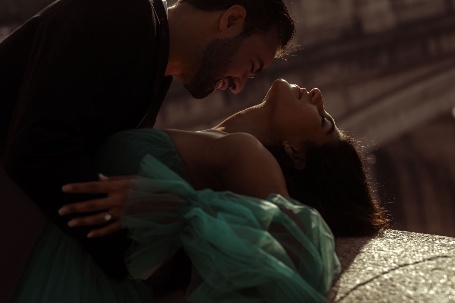 Dramatic low-light portrait featuring elegant evening wear and intimate embrace.