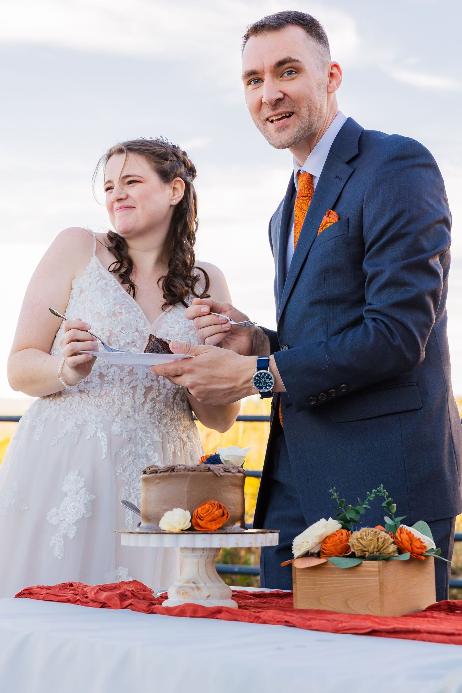 Happy newlyweds share dessert at their outdoor wedding reception.