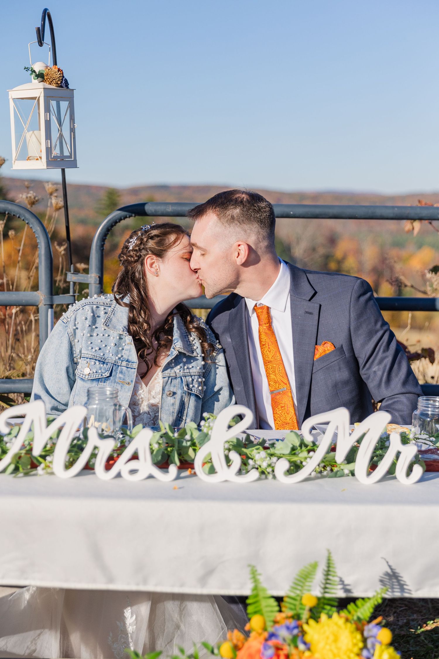 A romantic moment between newlyweds at their decorated outdoor wedding reception table.