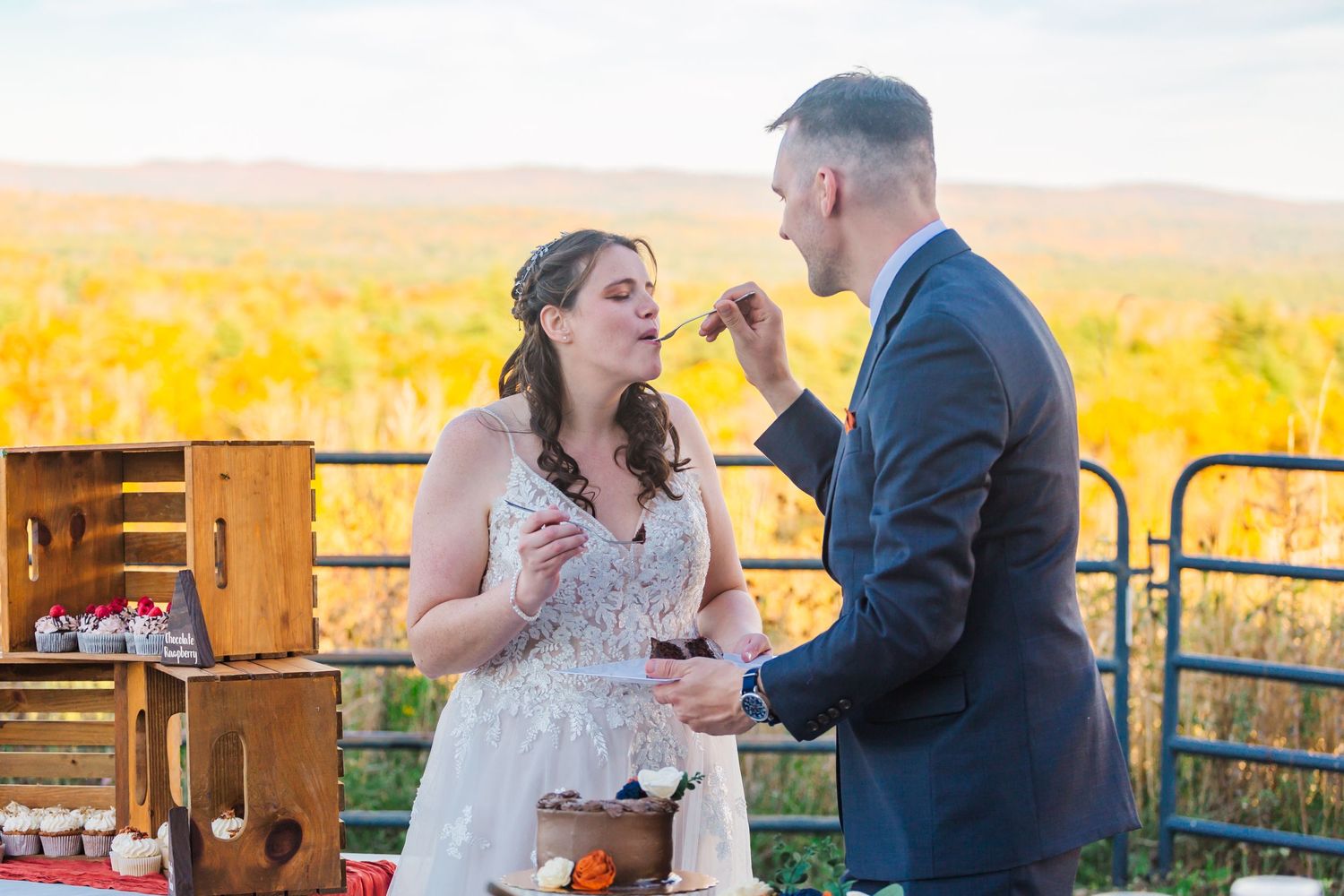 Couple sharing food and drinks at outdoor event with golden sunset backdrop.
