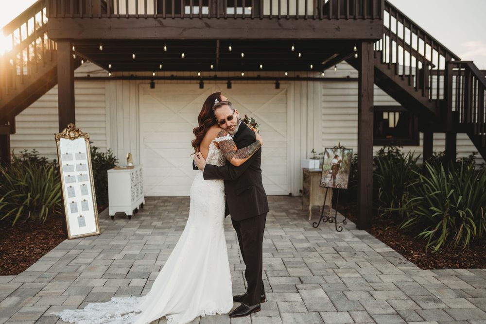A wedding couple shares an intimate moment under string lights at dusk.